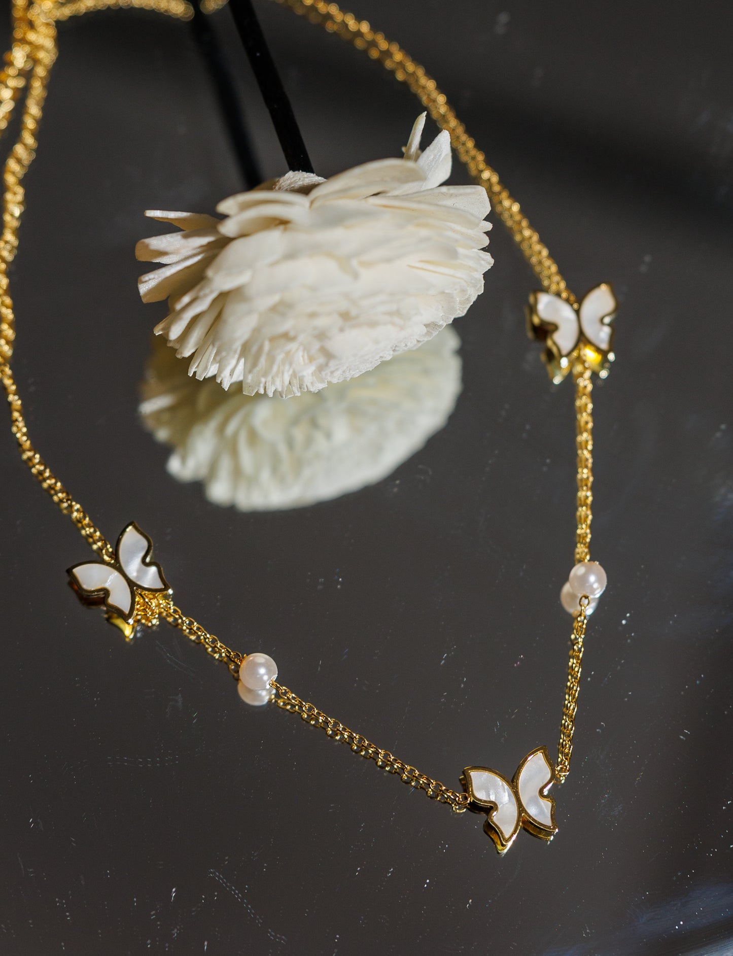 Round pearl necklace features an elegant butterfly design.