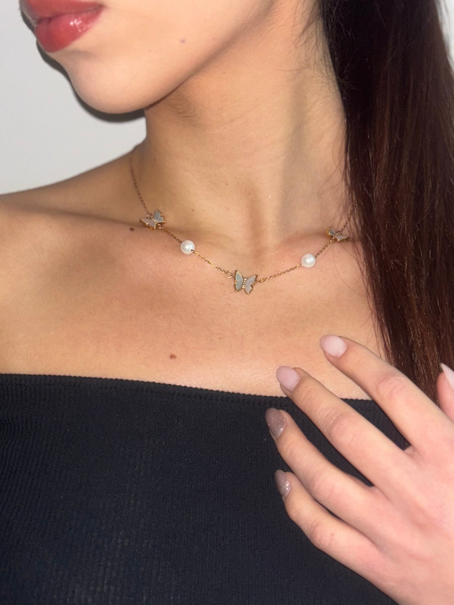 Round pearl necklace features an elegant butterfly design.